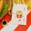 El mismo alfiler de esmalte de pescado y patatas fritas presentado en su tarjeta de soporte con elementos decorativos.