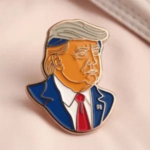 Eine Anstecknadel mit einem Bild von Donald Trump, das seine ikonische Frisur und seinen Ausdruck zeigt.