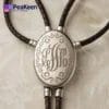 Elegant silver monogrammed necklace on a leather cord, designed as a bolo tie for a stylish touch.