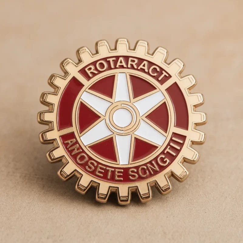 Un'elegante spilla Rotaract in rosso e oro, con la parola "rotatrici" in evidenza per il riconoscimento e l'orgoglio.