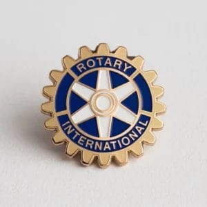 Pin del Rotary International esposto su una superficie bianca, che simboleggia l'appartenenza al Rotary Club.