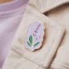 Un'elegante spilla color lavanda ornata da un vivace fiore viola, ideale per accessoriare abiti o borse.