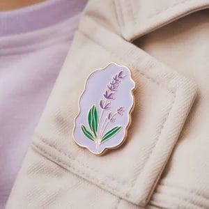 Un'elegante spilla color lavanda ornata da un vivace fiore viola, ideale per accessoriare abiti o borse.