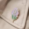 Un'affascinante spilla con un fiore viola, che rappresenta la collezione Lavender Pins, adatta a vari stili di moda.
