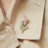 Una spilla color lavanda con un delicato disegno di fiori viola, perfetta per aggiungere un tocco di eleganza a qualsiasi abbigliamento.