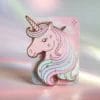 Spilla a forma di unicorno su un vivace sfondo rosa, che mette in mostra il suo design stravagante e i suoi dettagli colorati.