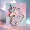 Spilla a forma di unicorno su un vivace sfondo rosa, che mette in mostra il suo design stravagante e i suoi dettagli colorati.