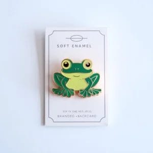 Colorful enamel pin of a frog, showcasing vibrant green hues and charming design elements.
